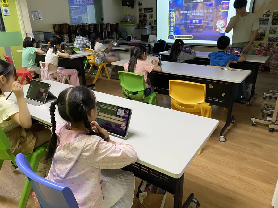 中心課室：學生以平板上課，前方投影幕顯示遊戲畫面